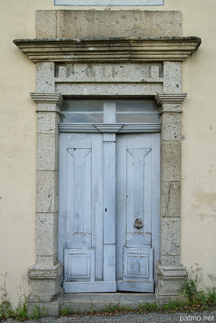 Image d'une ancienne porte en bois entoure de pierre sur une maison ardchoise