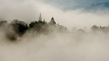 Photographie de la colline de Musiges mergeant du brouillard